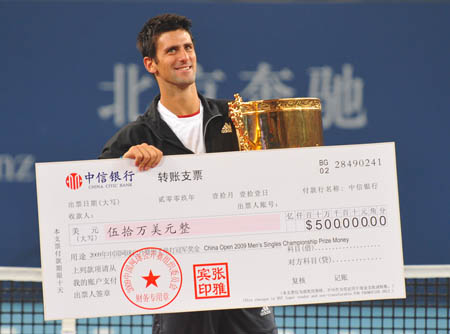 Novak Djokovic of Serbia holds up the trophy and bonus cheque during the awarding ceremony after winning the men's singles final against Marin Cilic of Croatia at the 2009 China Tennis Open Tournament in Beijing, Oct. 11, 2009.(Xinhua/Luo Xiaoguang)
