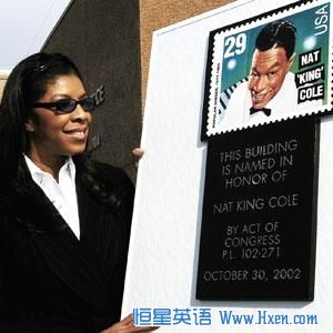 Singer Natalie Cole looks at a mock stamp and plaque following the renaming of a post office for her father Nat King Cole