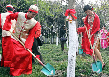 The newly-weds plant trees during a group wedding of traditional Chinese style in the Shajiabang Scenic Spot in Changshu, east China's Jiangsu Province, Nov. 16, 2008. 